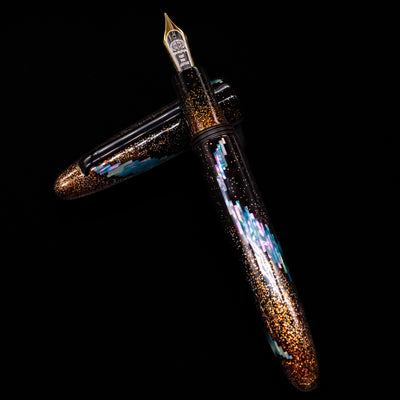 Taccia Miyabi Bon Bori Aurora Glimmer Fountain Pen laying on top of its cap in a crossed position showing full view of the entire uncapped pen.