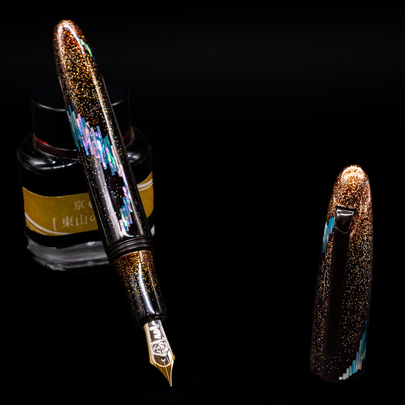 Taccia Miyabi Bon Bori Aurora Glimmer Fountain Pen leaning on an ink bottle uncapped showcasing the detailing on the nib.