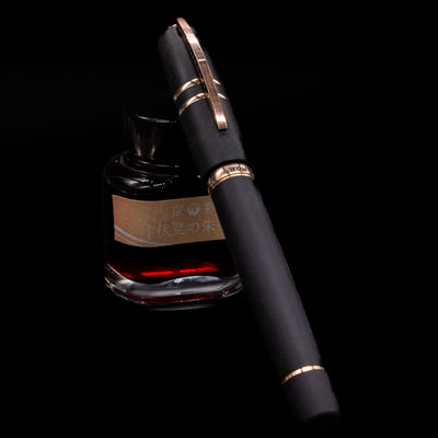Visconti Homo Sapiens Bronze Age Fountain Pen - Architect Nib capped, leaning against an ink bottle. 