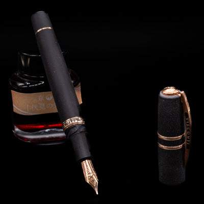 Visconti Homo Sapiens Bronze Age Fountain Pen - Architect Nib leaning on an ink bottle uncapped showcasing the detailing on the nib.