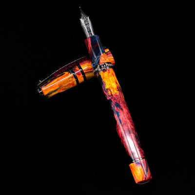 Visconti Homo Sapiens Earth Origins Fire edition uncapped fountain pen, laid across its cap, emphasizing the volcanic stone-inspired design and warm metallic accents.