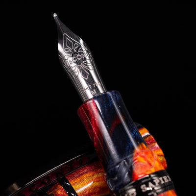 Detailed macro of the 18k gold nib, engraved with Visconti branding, glinting against the Fire resin on the Visconti Homo Sapiens Earth Origins Fire edition fountain pen.