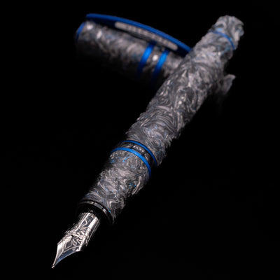 Visconti Homo Sapiens Fountain Pen - Carbon Abyssus laying across its own cap, crossed, with a focus on the nib.