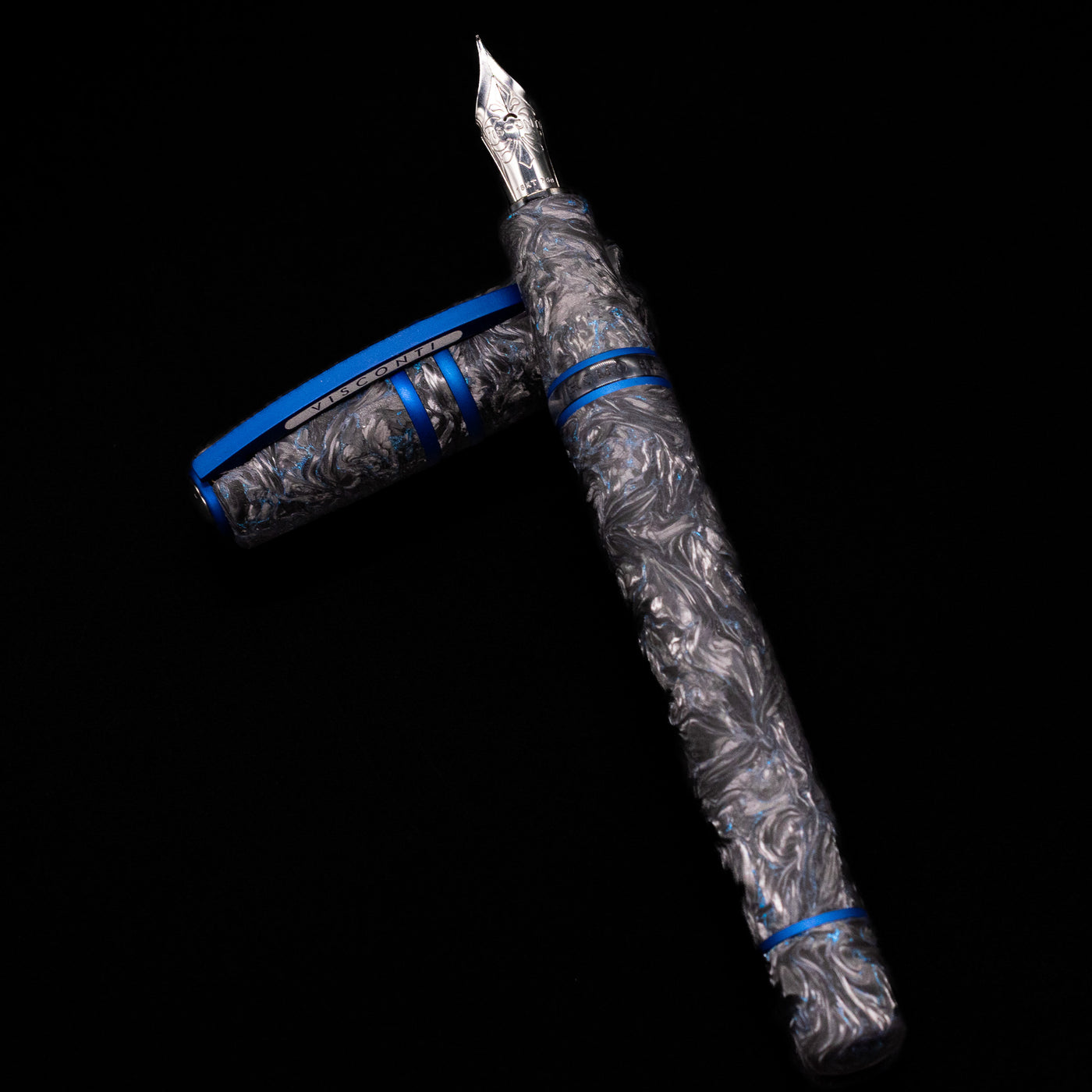 Visconti Homo Sapiens Fountain Pen - Carbon Abyssus laying on top of its cap in a crossed position showing full view of the entire uncapped pen.