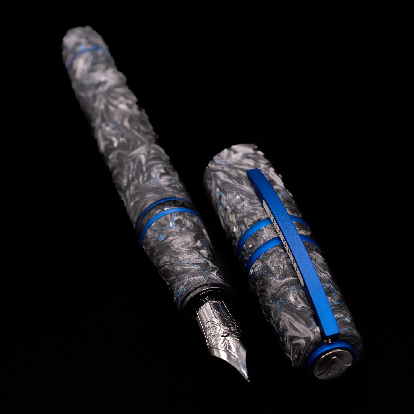 A full view of the Visconti Homo Sapiens Fountain Pen - Carbon Abyssus uncapped, with its cap laying next to the pen. 