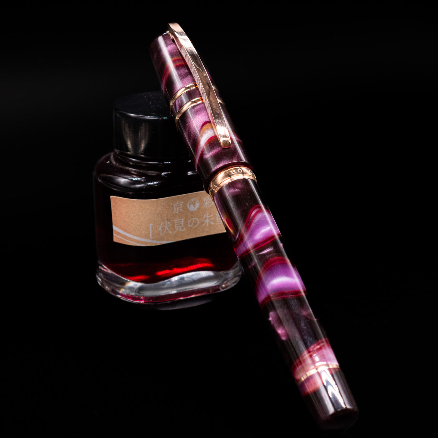 Visconti Homo Sapiens Iris Garden Fountain Pen capped, leaning against an ink bottle. 