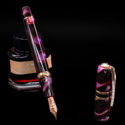 Visconti Homo Sapiens Iris Garden Fountain Pen leaning on an ink bottle uncapped showcasing the detailing on the nib.