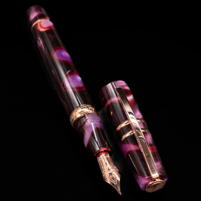  A full view of the Visconti Homo Sapiens Iris Garden Fountain Pen uncapped, with its cap laying next to the pen. 