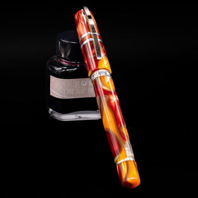 Visconti Homo Sapiens Limited Edition Fountain Pen - Arizona Sunset capped, leaning against an ink bottle. 