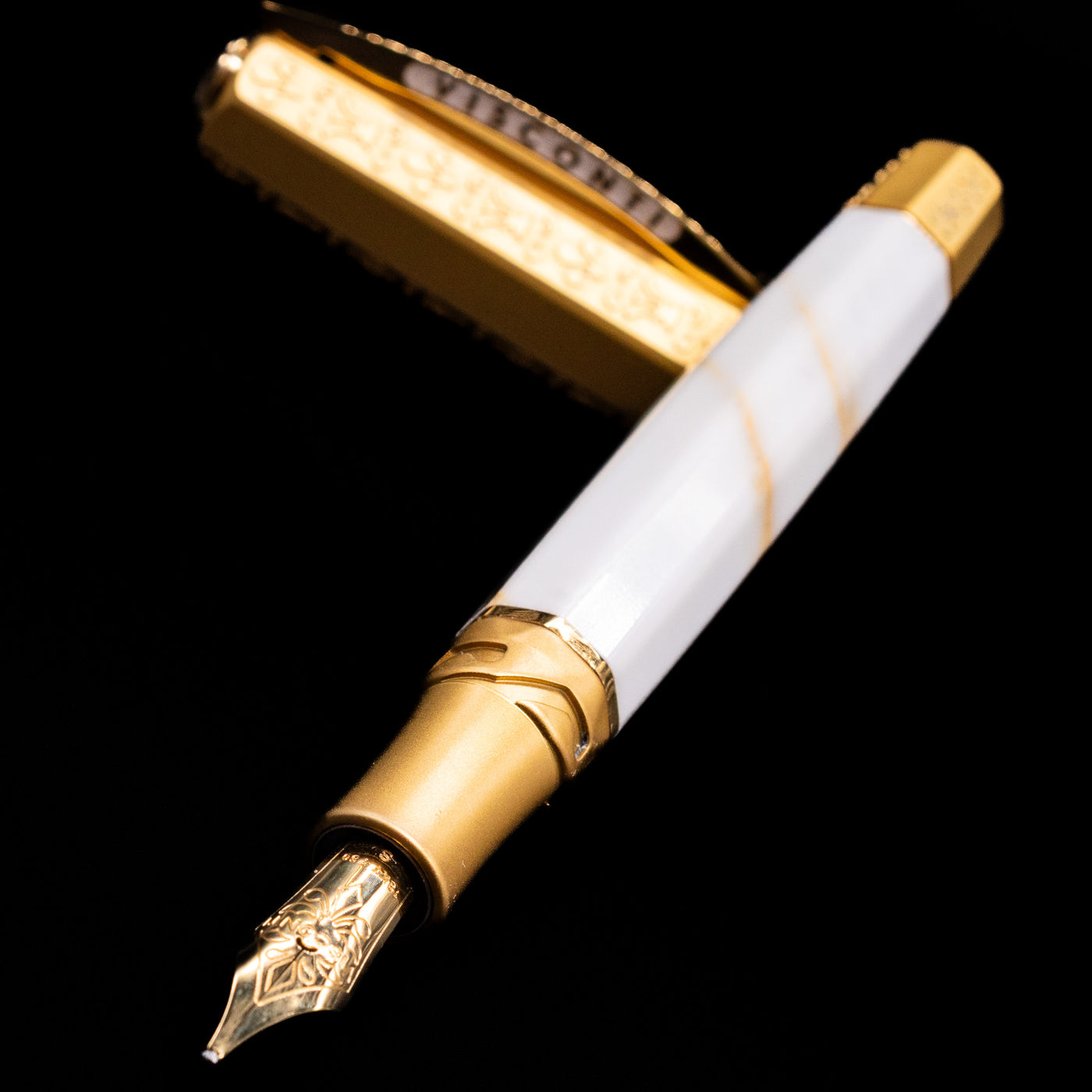 Visconti Il Magnifico Calacatta Gold Fountain Pen laying across its own cap, crossed, with a focus on the nib.