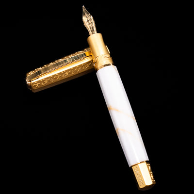 Visconti Il Magnifico Calacatta Gold Fountain Pen laying on top of its cap in a crossed position showing full view of the entire uncapped pen.