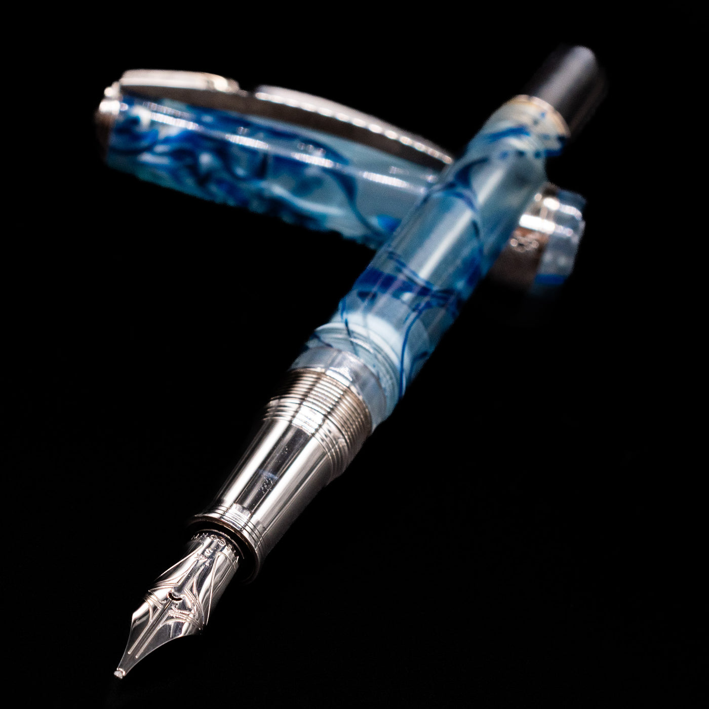 Visconti Manhattan Fountain Pen - Ice Blue laying across its own cap, crossed, with a focus on the nib.