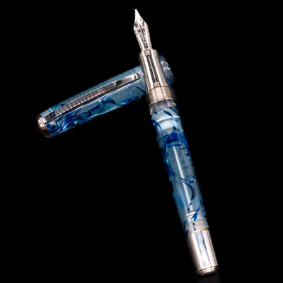 Visconti Manhattan Fountain Pen - Ice Blue laying on top of its cap in a crossed position showing full view of the entire uncapped pen.