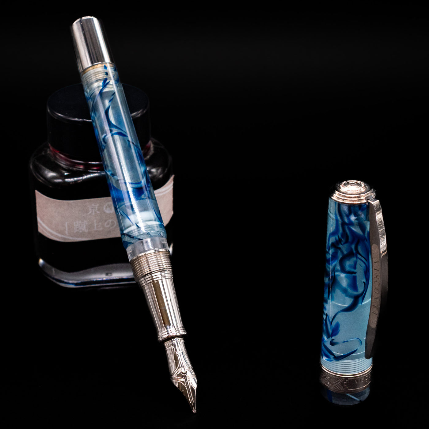 Visconti Manhattan Fountain Pen - Ice Blue leaning on an ink bottle uncapped showcasing the detailing on the nib.