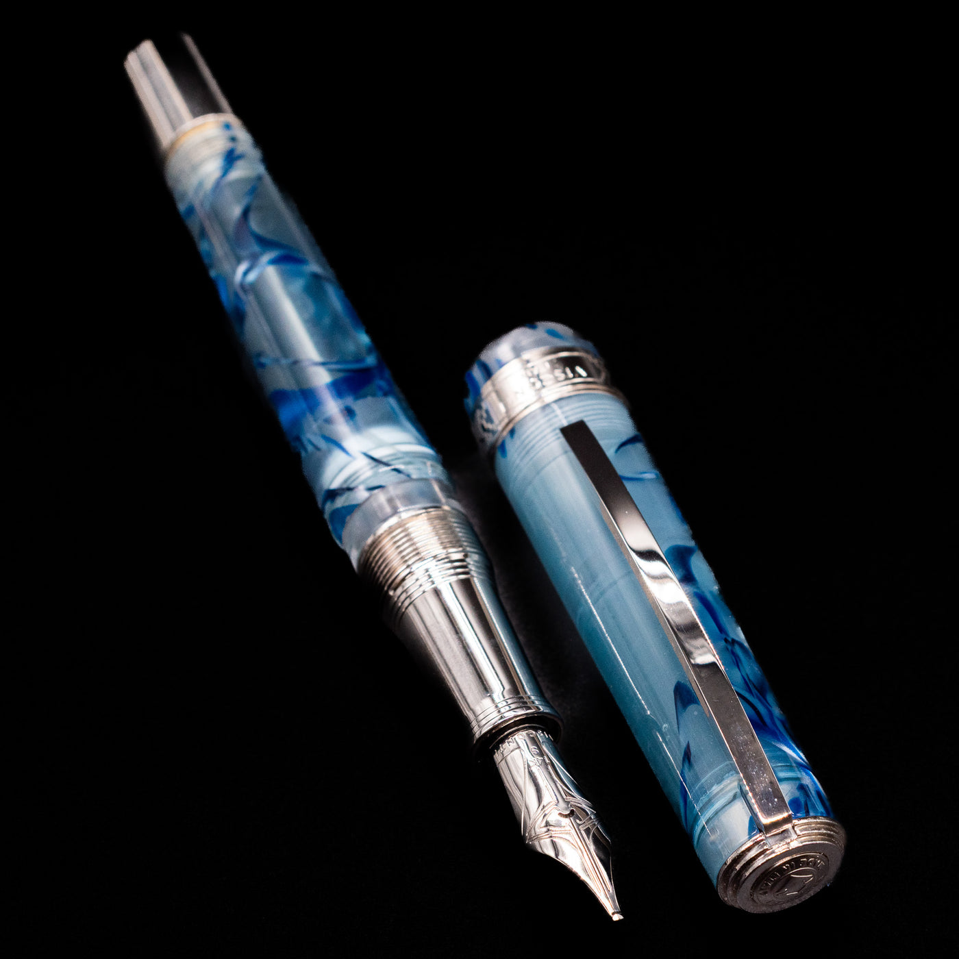 A full view of the Visconti Manhattan Fountain Pen - Ice Blue uncapped, with its cap laying next to the pen. 