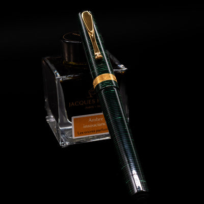 Visconti Manhattan Green Celluloid Fountain Pen - Preowned capped, leaning against an ink bottle. 