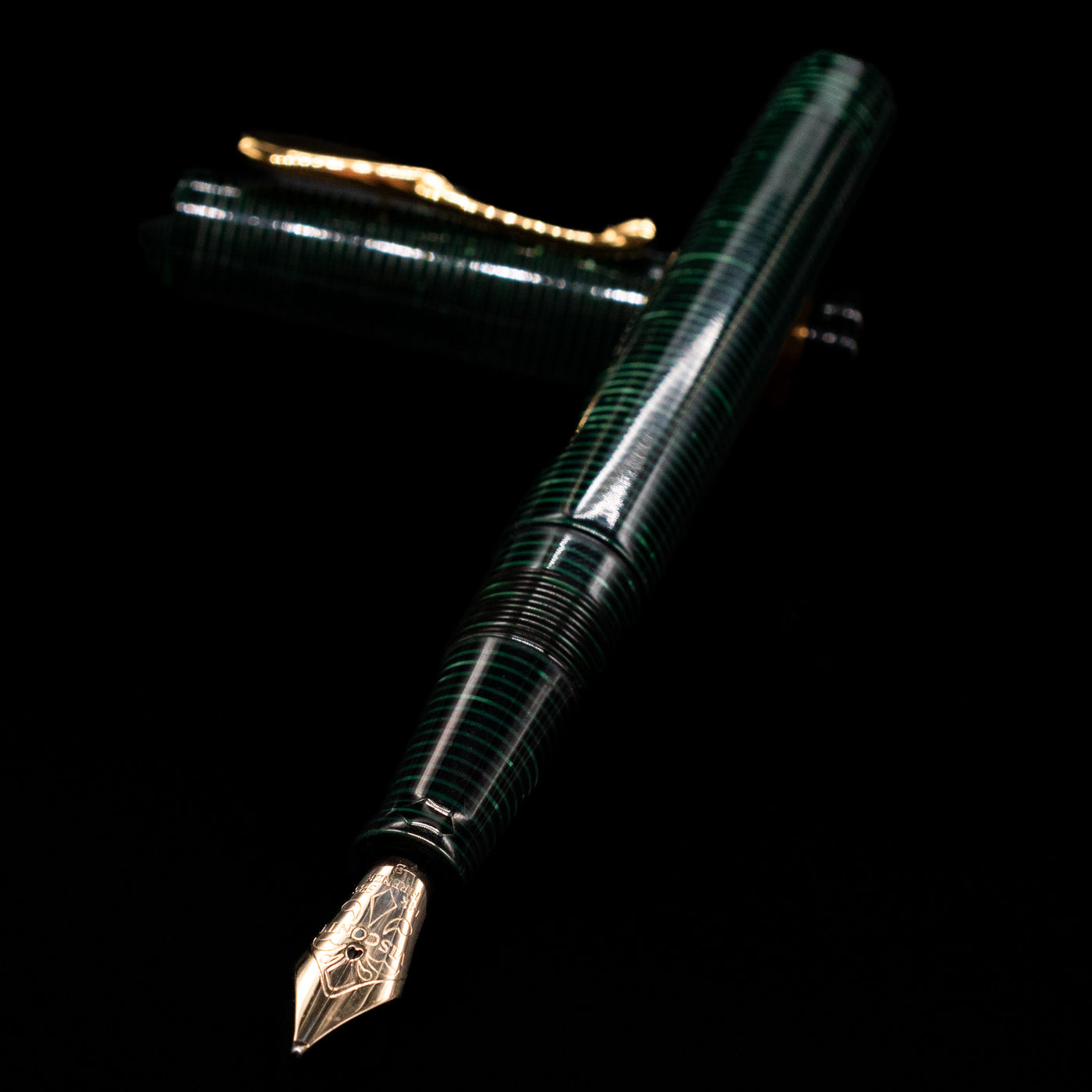 Visconti Manhattan Green Celluloid Fountain Pen - Preowned laying across its own cap, crossed, with a focus on the nib.