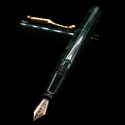Visconti Manhattan Green Celluloid Fountain Pen - Preowned laying across its own cap, crossed, with a focus on the nib.