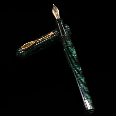 Visconti Manhattan Green Celluloid Fountain Pen - Preowned laying on top of its cap in a crossed position showing full view of the entire uncapped pen.