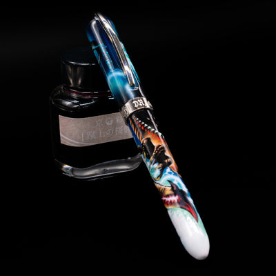 Visconti Mazzi Dragon Limited Edition Fountain Pen capped, leaning against an ink bottle. 