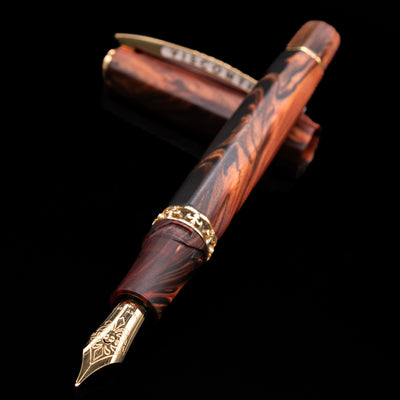Visconti Medici Briarwood Fountain Pen in Gold laying on top of its cap, crossed, with the focus on the intricate detailing on the gold nib.