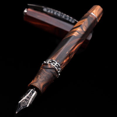 Visconti Medici Briarwood Fountain Pen in Ruthenium laying across its own cap, crossed, with a focus on the 18k nib.