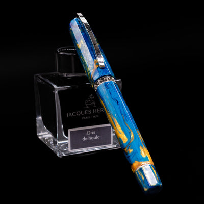 Visconti Medici Palazzo Vecchio fountain pen capped, resting diagonally on an ink bottle, showcasing its warm marbled resin and silver accents.