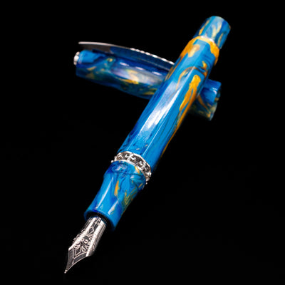 Visconti Medici Palazzo Vecchio fountain pen and cap crossed, with the nib in sharp focus against the warm marbled material.