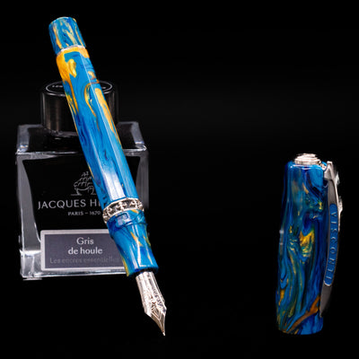 Visconti Medici Palazzo Vecchio fountain pen uncapped, nib exposed, leaning against an ink bottle, highlighting the intricate details of the marbled blue body.