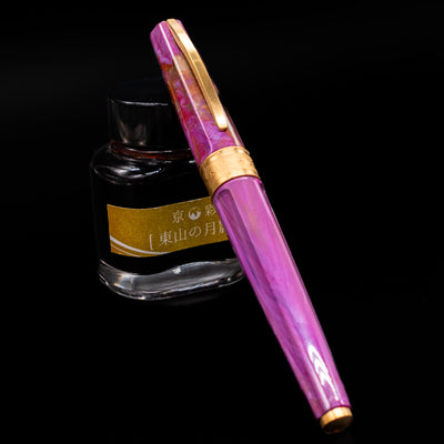 Visconti Mirage Mythos Fountain Pen - Aphrodite capped, leaning against an ink bottle. 