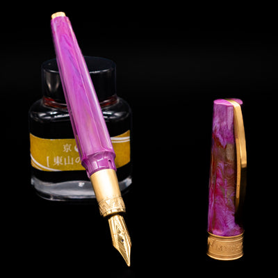 Visconti Mirage Mythos Fountain Pen - Aphrodite leaning on an ink bottle uncapped showcasing the detailing on the nib.