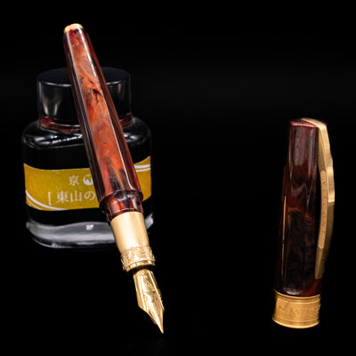 Visconti Mirage Mythos Fountain Pen - Apollo leaning on an ink bottle uncapped showcasing the detailing on the nib.