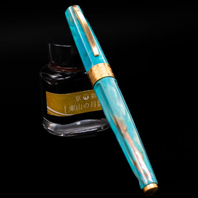 Visconti Mirage Mythos Fountain Pen - Athena capped, leaning against an ink bottle. 