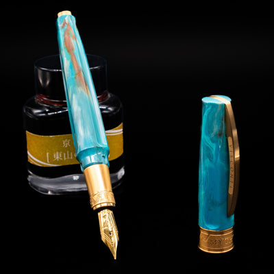 Visconti Mirage Mythos Fountain Pen - Athena leaning on an ink bottle uncapped showcasing the detailing on the nib.
