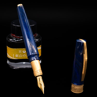 Visconti Mirage Mythos Fountain Pen - Zeus leaning on an ink bottle uncapped showcasing the detailing on the nib.