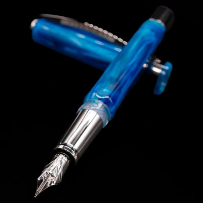 Visconti Opera Carousel Fountain Pen - Blue Cotton Candy laying across its own cap, crossed, with a focus on the nib.