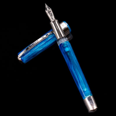  NAME laying across its own cap, crossed, with a focus on the nib.Visconti Opera Carousel Fountain Pen - Blue Cotton Candy
