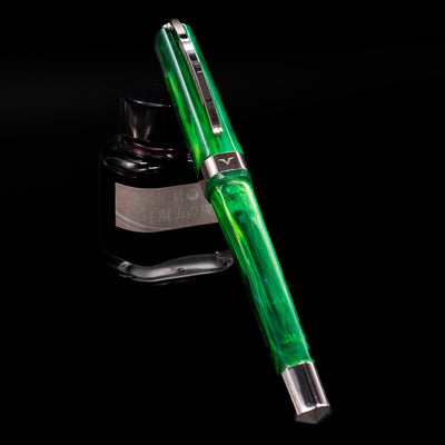 Visconti Opera Carousel Fountain Pen - Green Mint capped, leaning against an ink bottle. 