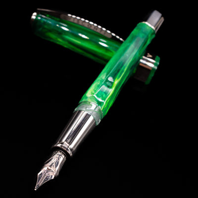 Visconti Opera Carousel Fountain Pen - Green Mint laying across its own cap, crossed, with a focus on the nib.