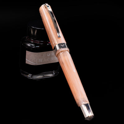 Visconti Opera Carousel Fountain Pen - Pink Blush capped, leaning against an ink bottle. 