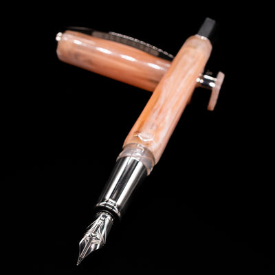 Visconti Opera Carousel Fountain Pen - Pink Blush laying across its own cap, crossed, with a focus on the nib.
