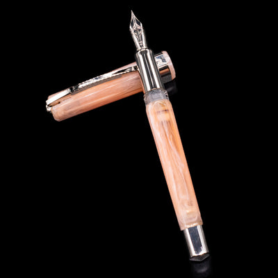 Visconti Opera Carousel Fountain Pen - Pink Blush laying on top of its cap in a crossed position showing full view of the entire uncapped pen.