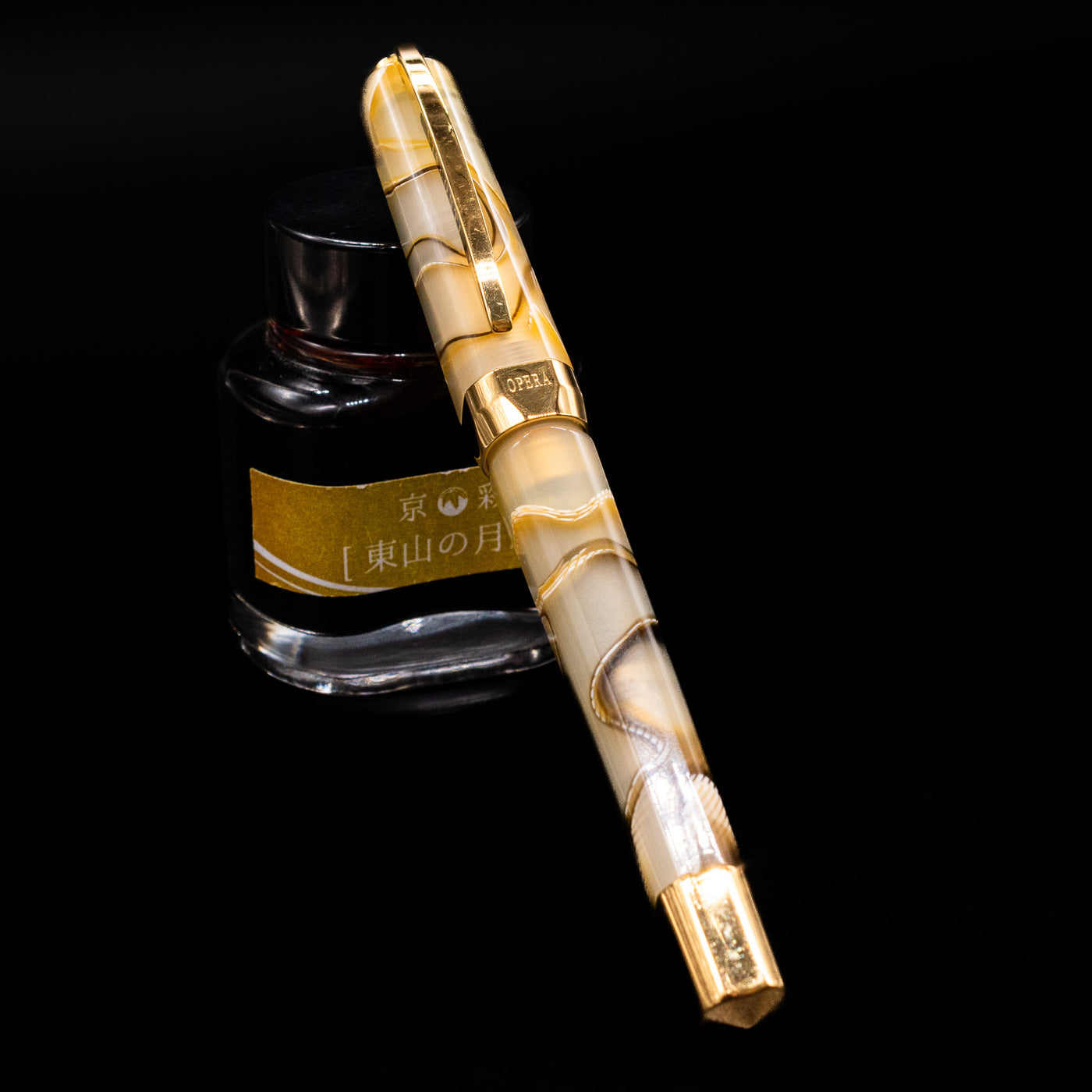 Visconti Opera Club Honey Almond Resin Fountain Pen - Preowned capped, leaning against an ink bottle. 