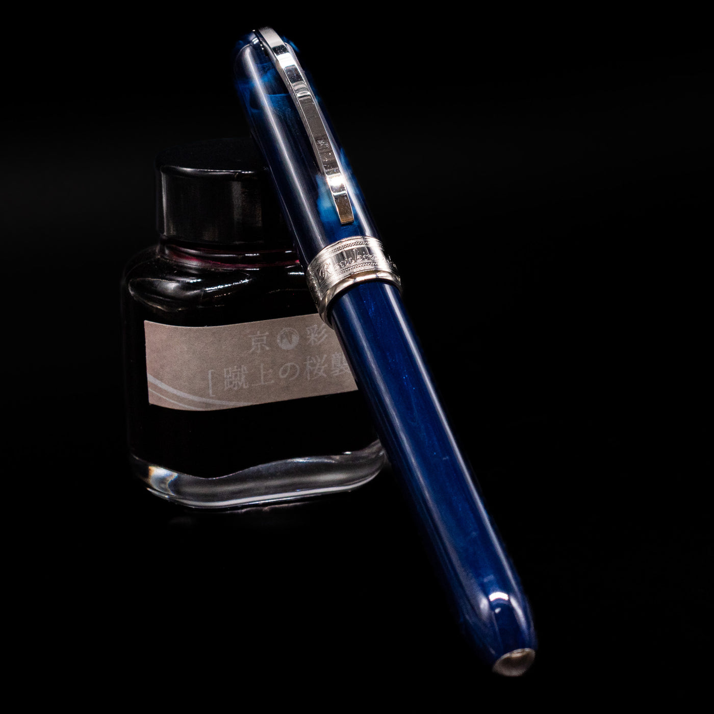 Visconti Rembrandt Blue Fountain Pen - Preowned capped, leaning against an ink bottle. 