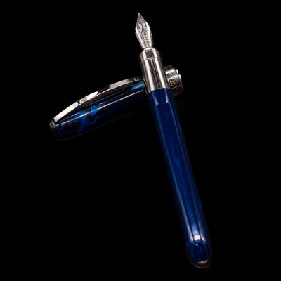 Visconti Rembrandt Blue Fountain Pen - Preowned laying on top of its cap in a crossed position showing full view of the entire uncapped pen.