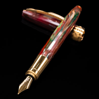Visconti Van Gogh Fountain Pen - Flowering Plum Orchard laying across its own cap, crossed, with a focus on the nib.