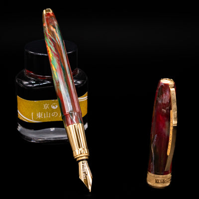 Visconti Van Gogh Fountain Pen - Flowering Plum Orchard leaning on an ink bottle uncapped showcasing the detailing on the nib.