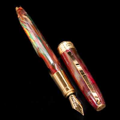 A full view of the Visconti Van Gogh Fountain Pen - Flowering Plum Orchard  uncapped, with its cap laying next to the pen. 