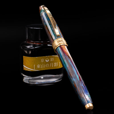 Visconti Van Gogh Fountain Pen - Oiran  capped, leaning against an ink bottle. 