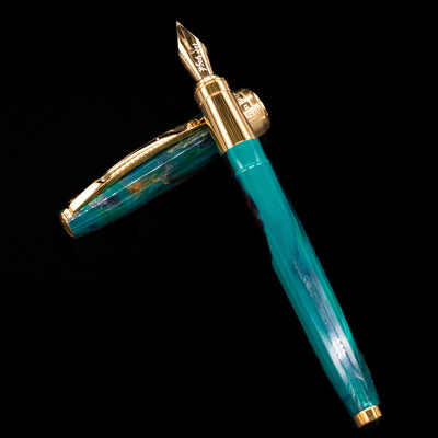 Visconti Van Gogh Fountain Pen - The Novel Reader laying on top of its cap in a crossed position showing full view of the entire uncapped pen.